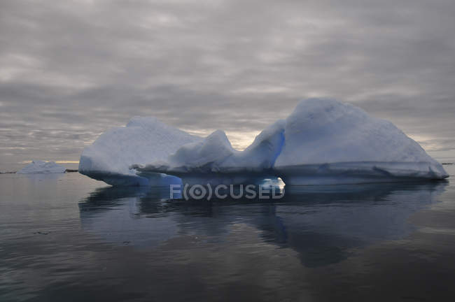 Iceberg e céu nublado refletido na água — Fotografia de Stock
