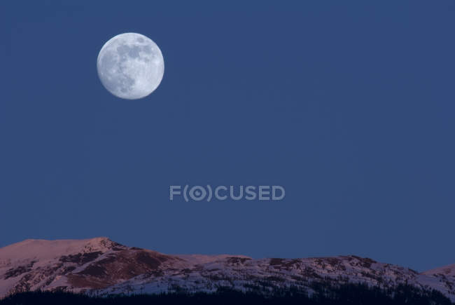 Luna llena sobre montañas en Alpenglow, New Aiyansh, Columbia Británica, Canadá - foto de stock