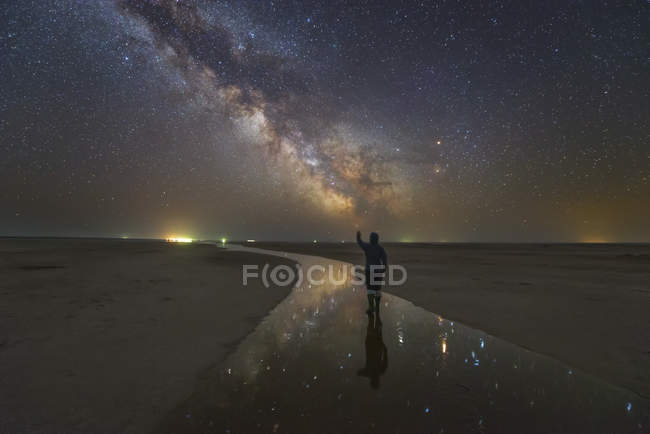 Uomo che cammina sul fiume salato di notte sotto la Via Lattea con stelle riflesse nel fiume, Russia — Foto stock