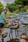 Чоловік кухар готує м'ясо барбекю на лісовому вогні — стокове фото