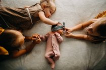 Sorelle coccole sul letto con un neonato — Foto stock