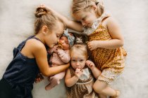 Sisters cuddling on the bed with a newborn baby — Stock Photo