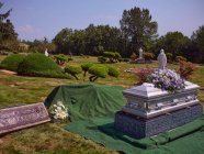Una bara con fiori si trova accanto a una tomba pronta per la sepoltura. — Foto stock