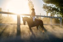 Kid monta um cavalo na aula de equitação, com itens de proteção — Fotografia de Stock