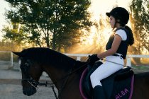 Ребенок ездит на лошади в классе верховой езды, с защитными предметами — стоковое фото