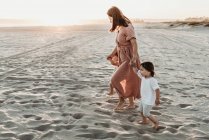 Madre a piedi con 2 anni ragazza in spiaggia durante il tramonto — Foto stock