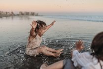 Heureuse fille de 2 ans éclaboussant dans l'eau de l'océan à la plage — Photo de stock