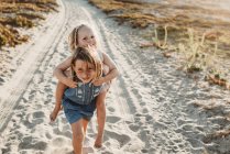 Jovens irmãs brincando na areia na praia durante o pôr do sol — Fotografia de Stock