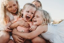 Крупним планом малюк сміється в оточенні молодих сестер — стокове фото
