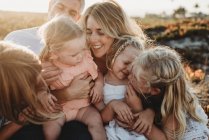 Lifestyle close up of family with young sisters sitting on beach — Stock Photo