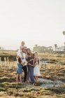 Retrato de estilo de vida de la familia con chicas jóvenes sonriendo al atardecer en la playa - foto de stock