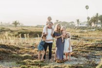 Traditiona retrato de família com meninas sorrindo ao pôr do sol da praia — Fotografia de Stock