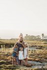 Lifestyle-Porträt einer Mutter mit jungen Mädchen, die bei Sonnenuntergang am Strand lächeln — Stockfoto