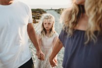 Menina séria fazendo cara triste andando com os pais na praia — Fotografia de Stock