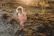 Retrato de estilo de vida de una niña caminando al atardecer en la playa - foto de stock