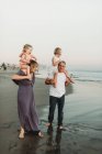 Lifestyle image of mother and father holding young daughters on should — Stock Photo