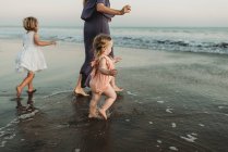 Blick hinter die Kulissen einer jungen Familie, die bei Sonnenuntergang dem Meer entgegen geht — Stockfoto