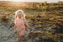 Porträt eines kleinen Mädchens mit Zöpfen, das am Strand in die Kamera lächelt — Stockfoto