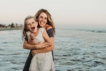 Madre abrazando a chica joven con pecas en el océano - foto de stock