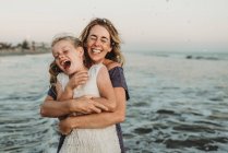 Mãe abraçando jovem com sardas no oceano — Fotografia de Stock