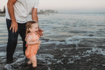 Kleinkind planscht bei Sonnenuntergang mit Vater im Meer — Stockfoto