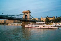 Sunset cruise boat by Szchenyi Chain Bridge and four seasons hotel — Stock Photo
