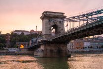 Puente de la Cadena Szechenyi al atardecer con el distrito del castillo de Buda - foto de stock