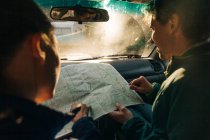 Una joven pareja mira el mapa en un viaje por carretera. - foto de stock