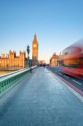 Red double-decker bus passes on Westminster Bridge, in front of Westminster Palace and clock tower of Big Ben (Elizabeth Tower), London, England, United Kingdom — Stock Photo