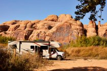 An RV parked in front of a red rock wall in Moab, Utah. — Stock Photo