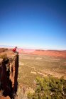 Un homme est assis au bord d'une grande falaise surplombant Monument Valley. — Photo de stock