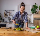 Mujer ama de casa joven y hermosa cocina en una cocina - foto de stock