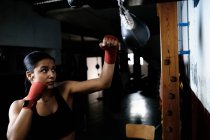 Mujer joven practicando boxeo en el gimnasio - foto de stock
