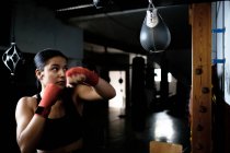 Jeune femme pratiquant la boxe au gymnase — Photo de stock
