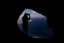 Silhouette d'un homme faisant une photo d'une grotte dans les falaises de Famara. — Photo de stock