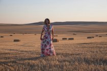 Woman standing in wheat field at sunset — Stock Photo