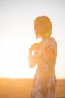 Жінка спостерігає за сухим полем на заході сонця — стокове фото