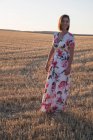 Frau beobachtet das trockene Feld bei Sonnenuntergang — Stockfoto