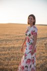 Женщина наблюдает за сухим полем на закате — стоковое фото