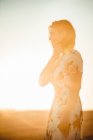 Donna che osserva il campo asciutto al tramonto — Foto stock