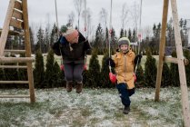 Mother and son playing on a swing together outside in the snow — Stock Photo