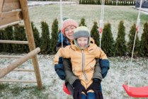 Mother and son laughing swinging on a swing together outside — Stock Photo