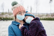 Madre llevando hijo con mascarillas en la cara como protección contra virus y gripe - foto de stock