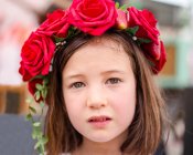 Portrait of a serious little girl with a wreath of roses in her hair — Stock Photo