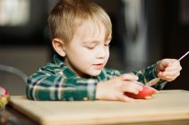 Kleiner Junge isst mit einem Löffel eine Drachenfrucht. — Stockfoto