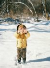 A little boy with cold hands on a snowy winter day. — Stock Photo