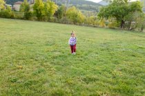 Lindo pequeño niño sosteniendo una pequeña flor caminando en el prado - foto de stock