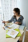 Тысячелетняя девочка рисует сказочные образы на бумаге, сидя дома — стоковое фото