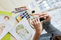 Millennial fille dessine des images fabuleuses sur papier tout en étant assis à la maison — Photo de stock