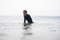 Жінка сміється в океані, чекаючи серфінгу — стокове фото